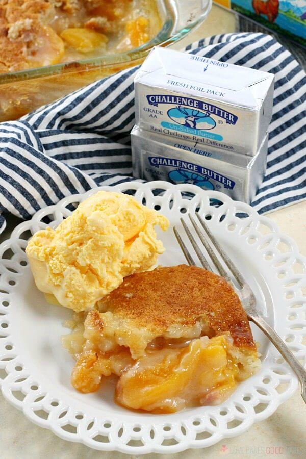 Easy Southern Peach Cobbler en un plato con helado y un tenedor y dos cubos de Challenge Butter.