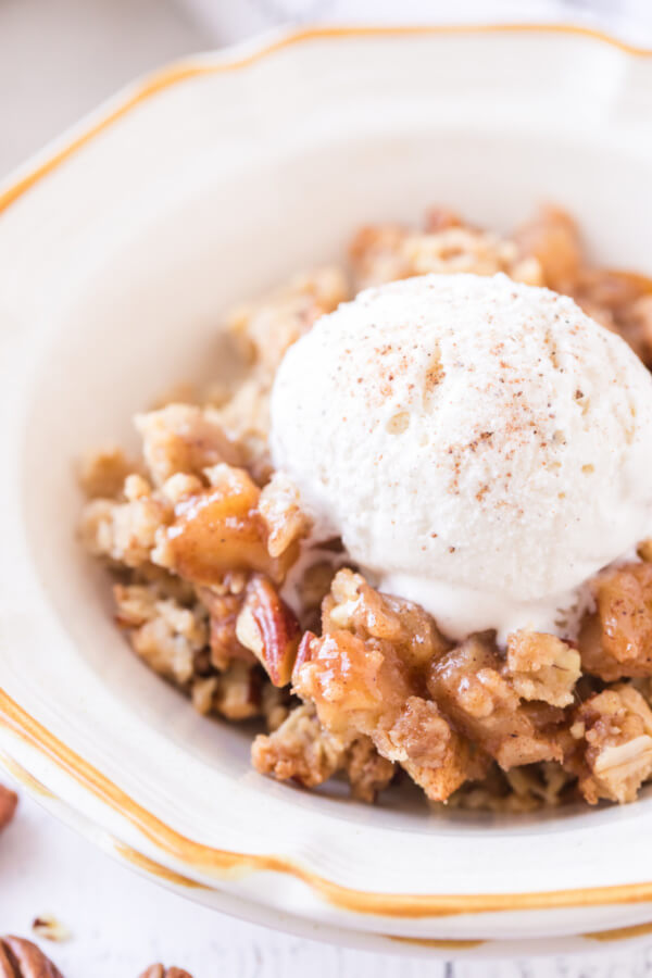 porción de crumble de manzana en un tazón cubierto con una bola de helado