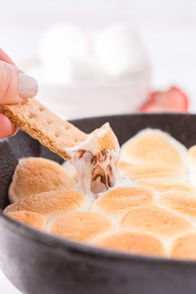 Graham Cracker recolectando una mezcla de chocolate y malvaviscos de una sartén de hierro fundido