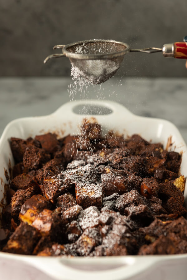 espolvorear con azúcar glas sobre el budín de pan de chocolate terminado