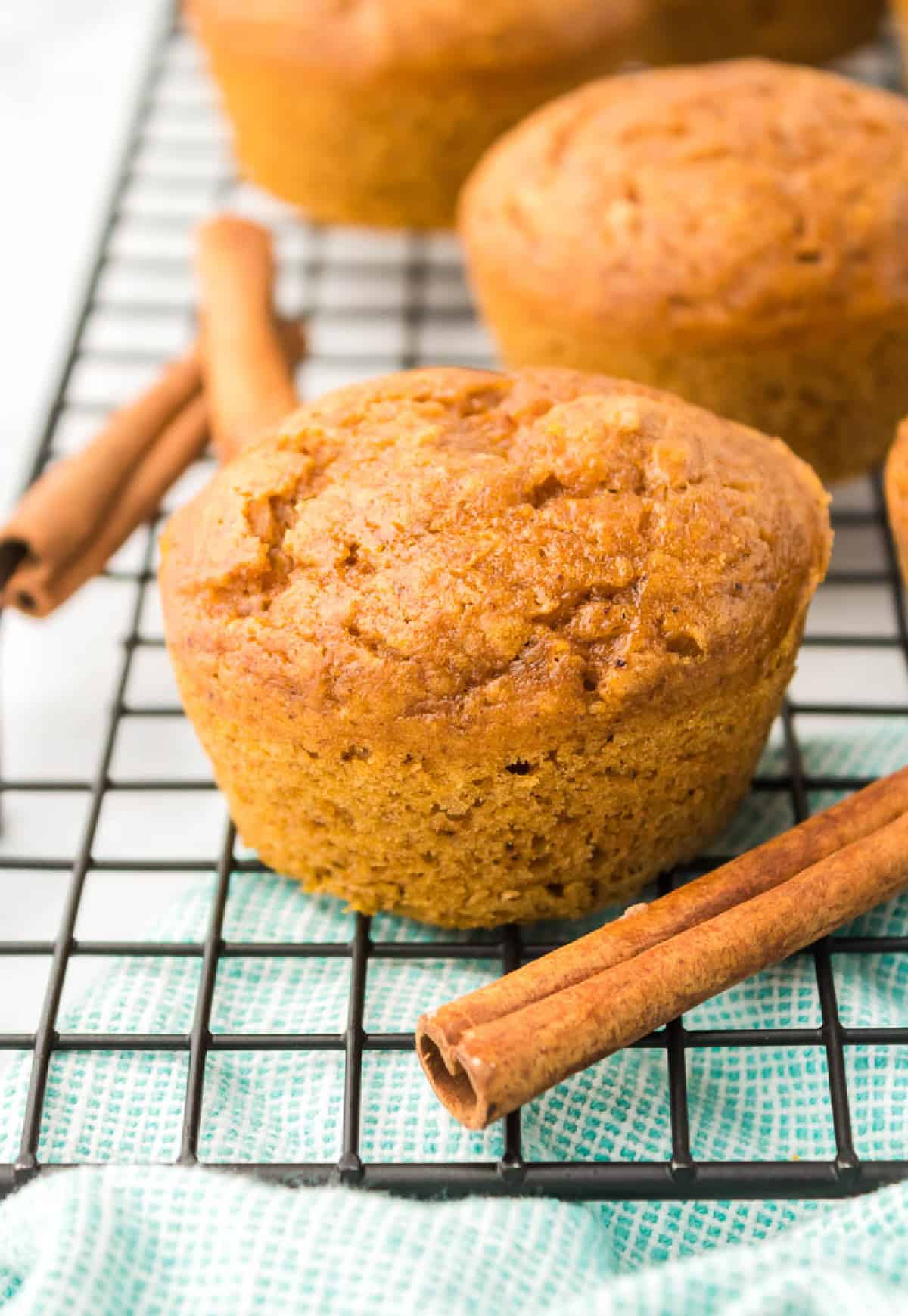 Onw muffins en una rejilla con palitos de canela.