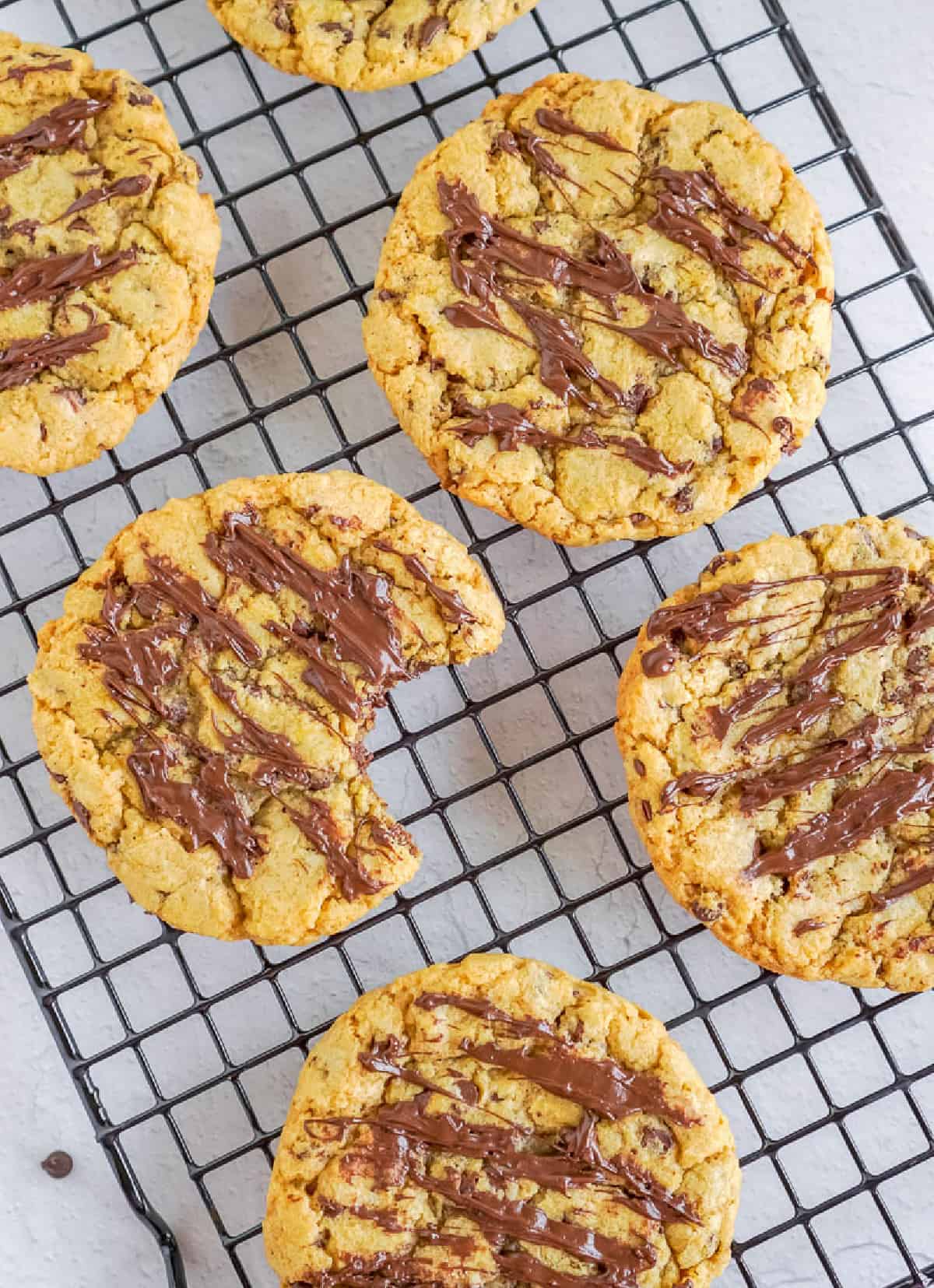 Galletas de chispas de chocolate con calabaza en una rejilla para enfriar, una con un bocado.