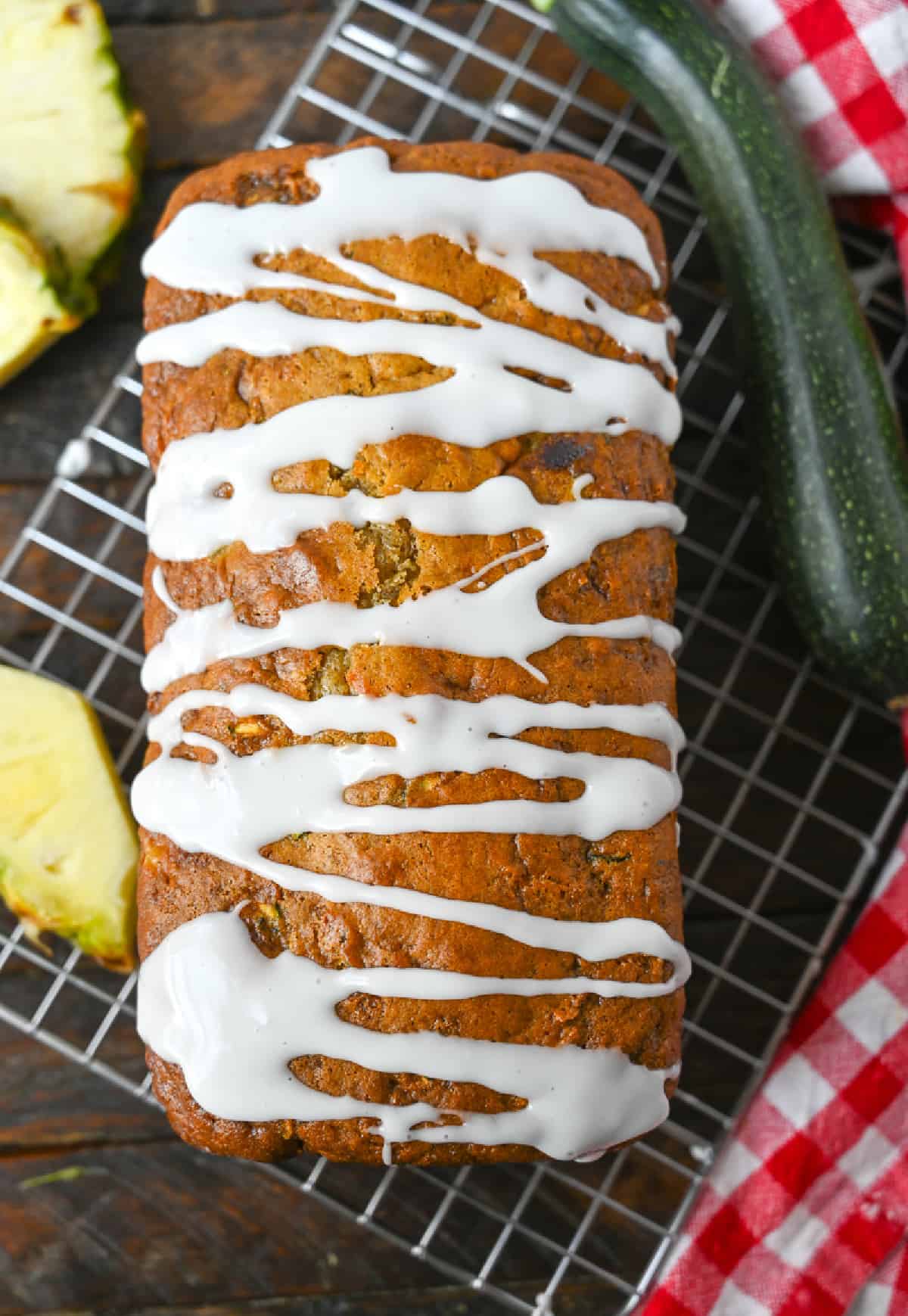 Un trozo de pan de piña y calabacín con un glaseado espolvoreado encima.