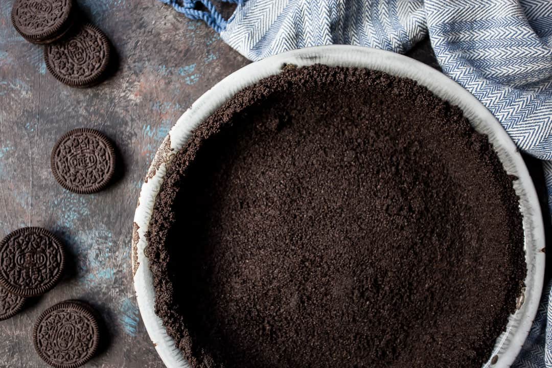 Corteza Oreo para pastel o tarta de queso, sobre fondo oscuro con toalla azul.