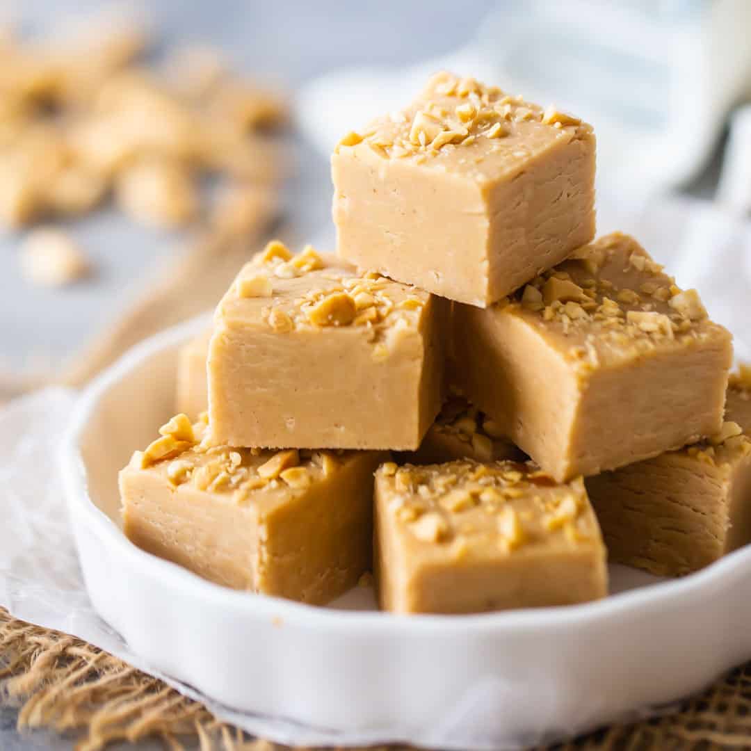 Fudge de mantequilla de maní cortado en cuadrados y colocado en un plato blanco.