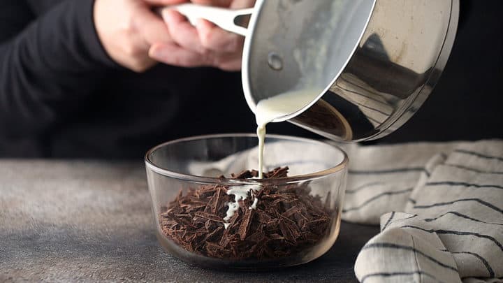 Verter la nata caliente sobre el chocolate troceado para hacer la ganache.