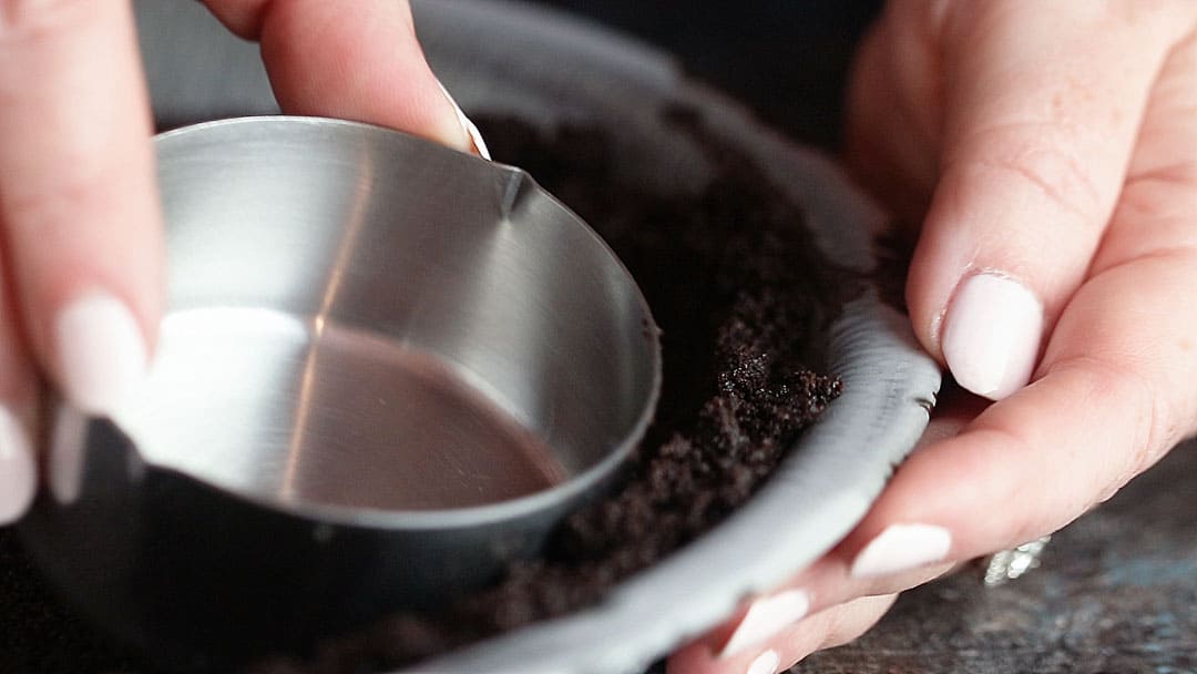 Primer plano de dar forma a la corteza de pastel de Oreo con una taza medidora.