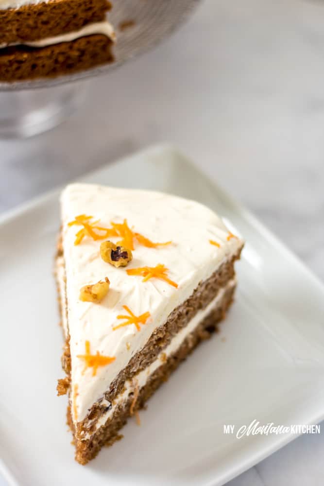 pastel de zanahoria bajo en carbohidratos en un plato blanco con zanahorias ralladas y nueces