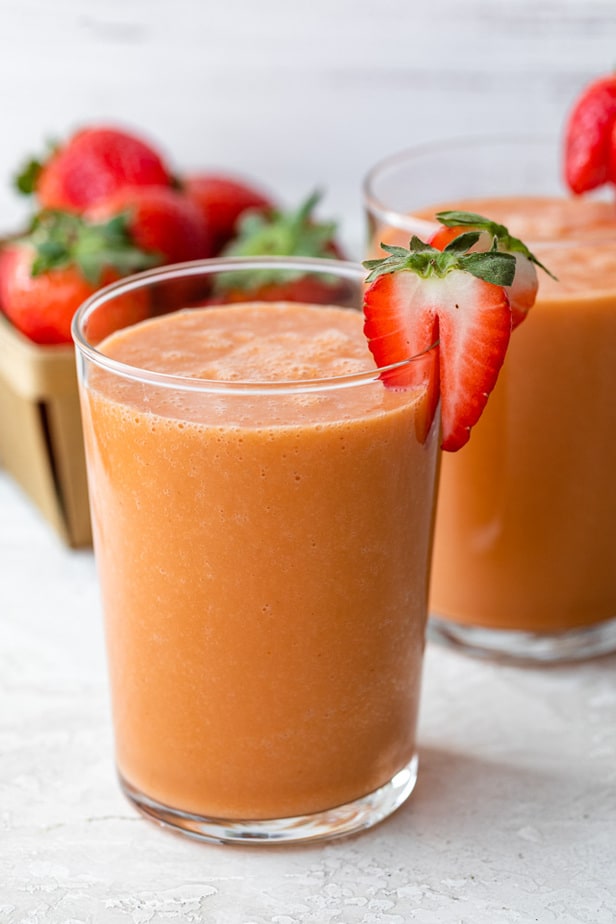 Un batido de fresa y mango adornado con fresas frescas