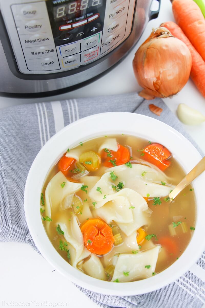 tazón de sopa de fideos con pollo con una olla instantánea en el fondo