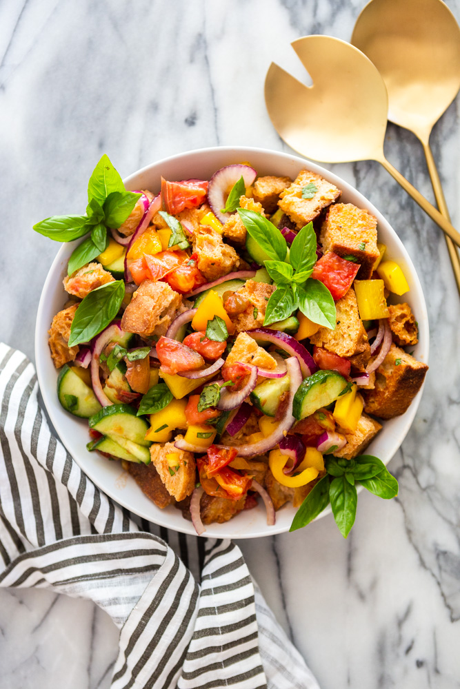 Ensalada de pan Panzanella en un tazón blanco sobre un mostrador de mármol