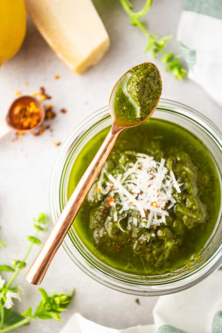 Cucharas de salsa de pasta al pesto del frasco con una cuchara de cobre.