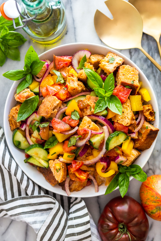 Ensalada de pan Panzanella en un tazón blanco sobre un fondo de mármol.