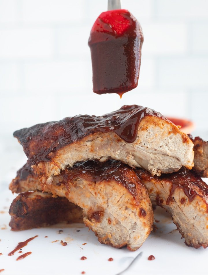 costillas de freidora apiladas con salsa de barbacoa que gotea del cepillo